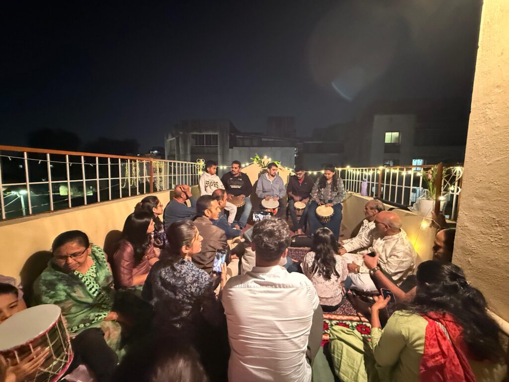 Home live music concert with multiple jembe players performing on a terrace during a private family event.