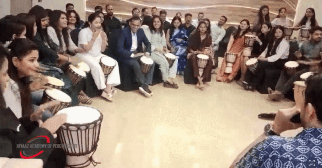 Corporate Team Building Activities in Pune: How Rhythm and Music Can Transform Workplace Teams 4 Employees participating in a Djembe drum circle during corporate team building activities by Riyaaz Academy in Pune